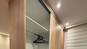 Un closet amplio con puertas corredizas, una barra para colgar ropa y una cama con cubrecama gris.