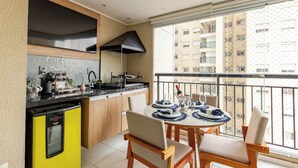 Una cocina moderna con lavavajillas integrado, un comedor con mesa redonda y sillas, y un balcón con vistas a la ciudad.