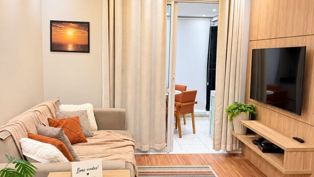 Una sala de estar moderna con un sofá, televisor y una mesita con un letrero.