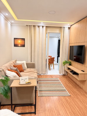 A modern living room with a sofa, TV, and a small table with a sign.
