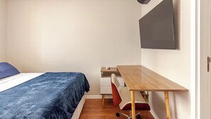 Un dormitorio con cama, escritorio y silla.
