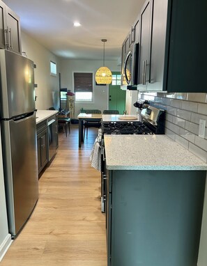 A modern kitchen with stainless steel appliances, a central island, and a dining area with a table and chairs. - Cozy 2-bedroom cottage between Wildwood & Cape May NJ (Rio Grande)