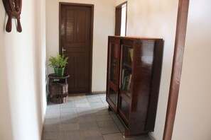A hallway with a wooden door, a wicker basket with a plant, and a wooden cabinet with glass doors. - The best option for your vacation. (Caponga)