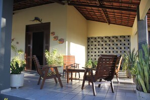 An outdoor seating area with wooden chairs and tables, potted plants, and a decorative wall. - The best option for your vacation. (Caponga)