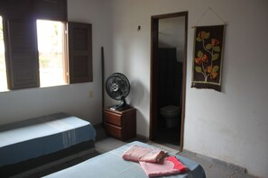 Ein Zimmer mit einem Bett, einem Ventilator, einem Kleiderschrank und einer Toilette.