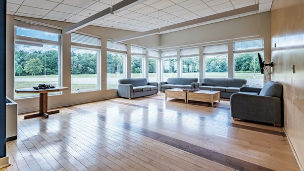 Un salón amplio con ventanas grandes, un sofá gris y una mesa de centro de madera.