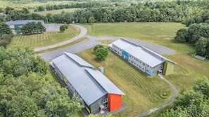 Ein Luftbild eines modernen Gebäudekomplexes mit mehreren Bauten, Parkplätzen und umliegender Grünfläche.