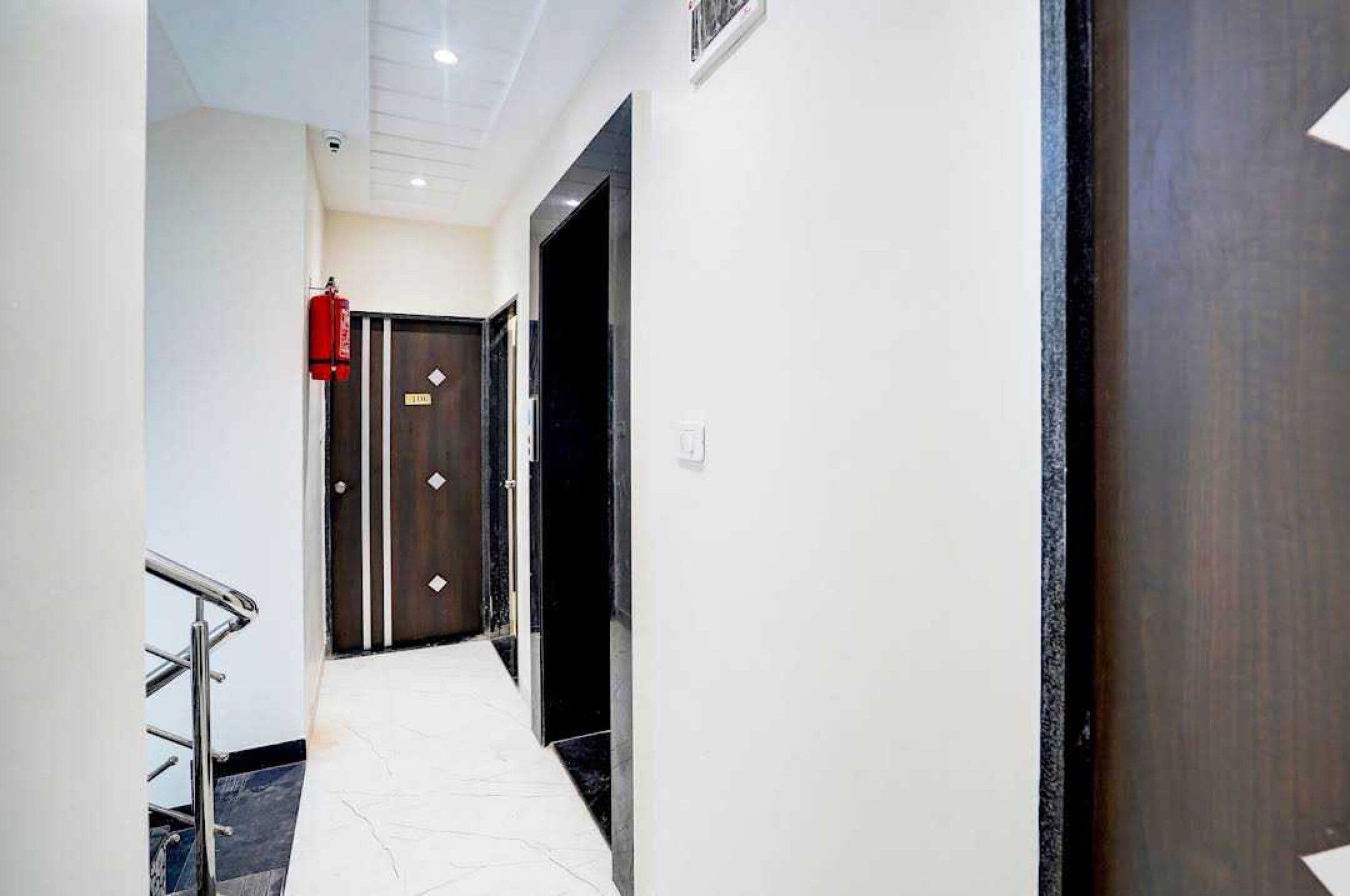 A hallway with a fire extinguisher, a door with a sign, and a metal handrail.