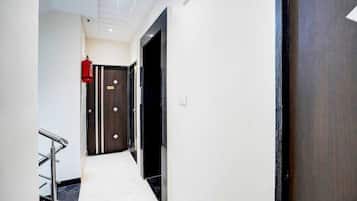 A hallway with a fire extinguisher, a door with a sign, and a metal handrail.