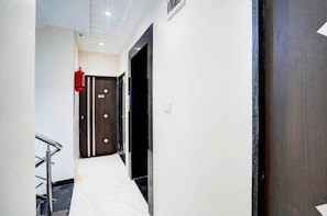 A hallway with a fire extinguisher, a door with a sign, and a metal handrail. - Classic Wardha Road Nagpur (Nagpur)