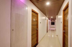 A long hallway with wooden doors and a tiled floor, leading to a room. - Classic Wardha Road Nagpur (Nagpur)