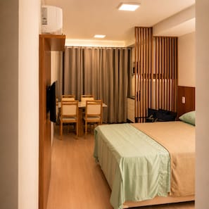 A hotel room with a bed, a desk with chairs, a television, and a curtain. - Vrbo Property (Rio de Janeiro)