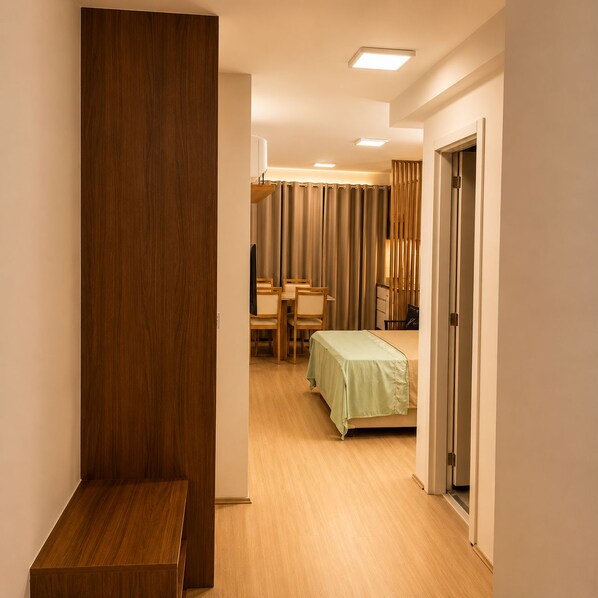 A hotel room with a bed, a desk, and a chair. There is a wooden panel on the left side and a door on the right. - Vrbo Property (Rio de Janeiro)