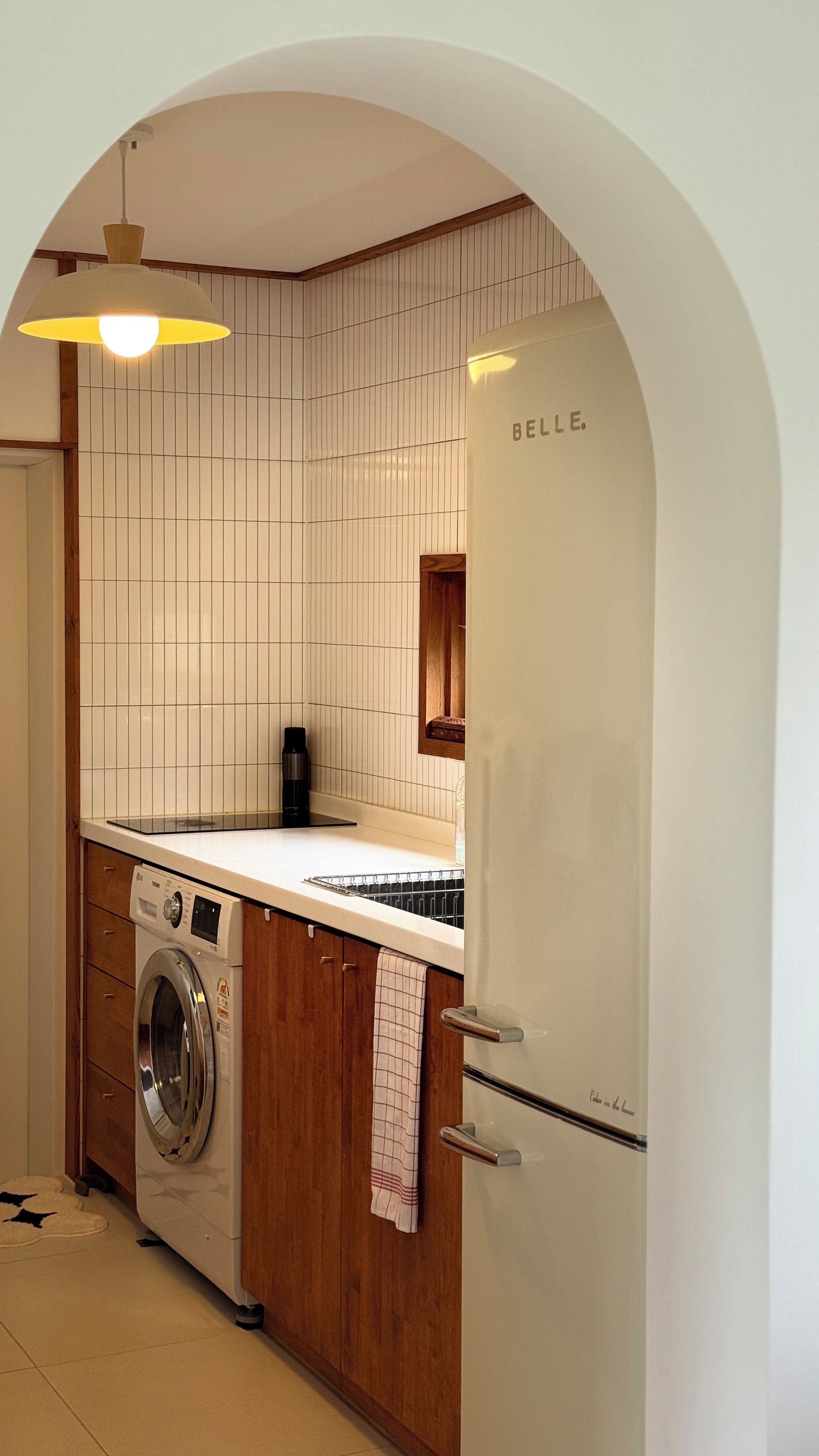 Eine kompakte Küche mit Waschmaschine, Kühlschrank und einer Holzarbeitsplatte.