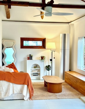 A modern bedroom with a bed, bedside table, lamp, and a view of the outdoors.