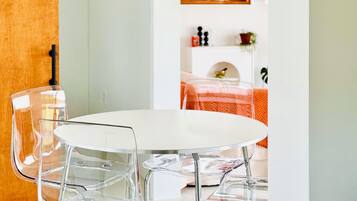 Un espace repas avec une table ronde, des chaises transparentes et un luminaire suspendu.