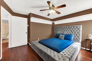 Ein Schlafzimmer mit einem großen Bett, einem Deckenventilator und Holzboden.