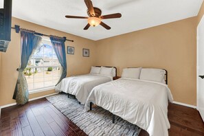 A bedroom with two beds, a ceiling fan, a window with curtains, and a view of the outside. - New! Luxury Spacious Home 4 Beds 2 Bath 20 Min DTX (Balch Springs)