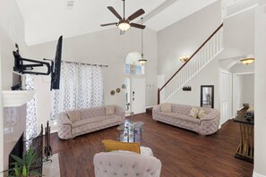 Un salon spacieux avec deux canapés, une table basse et un ventilateur de plafond.