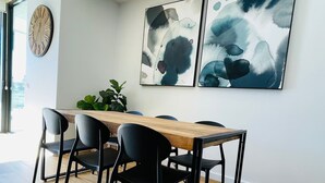 Et spiseområde med et træbord, sorte stole og abstrakt vægkunst.