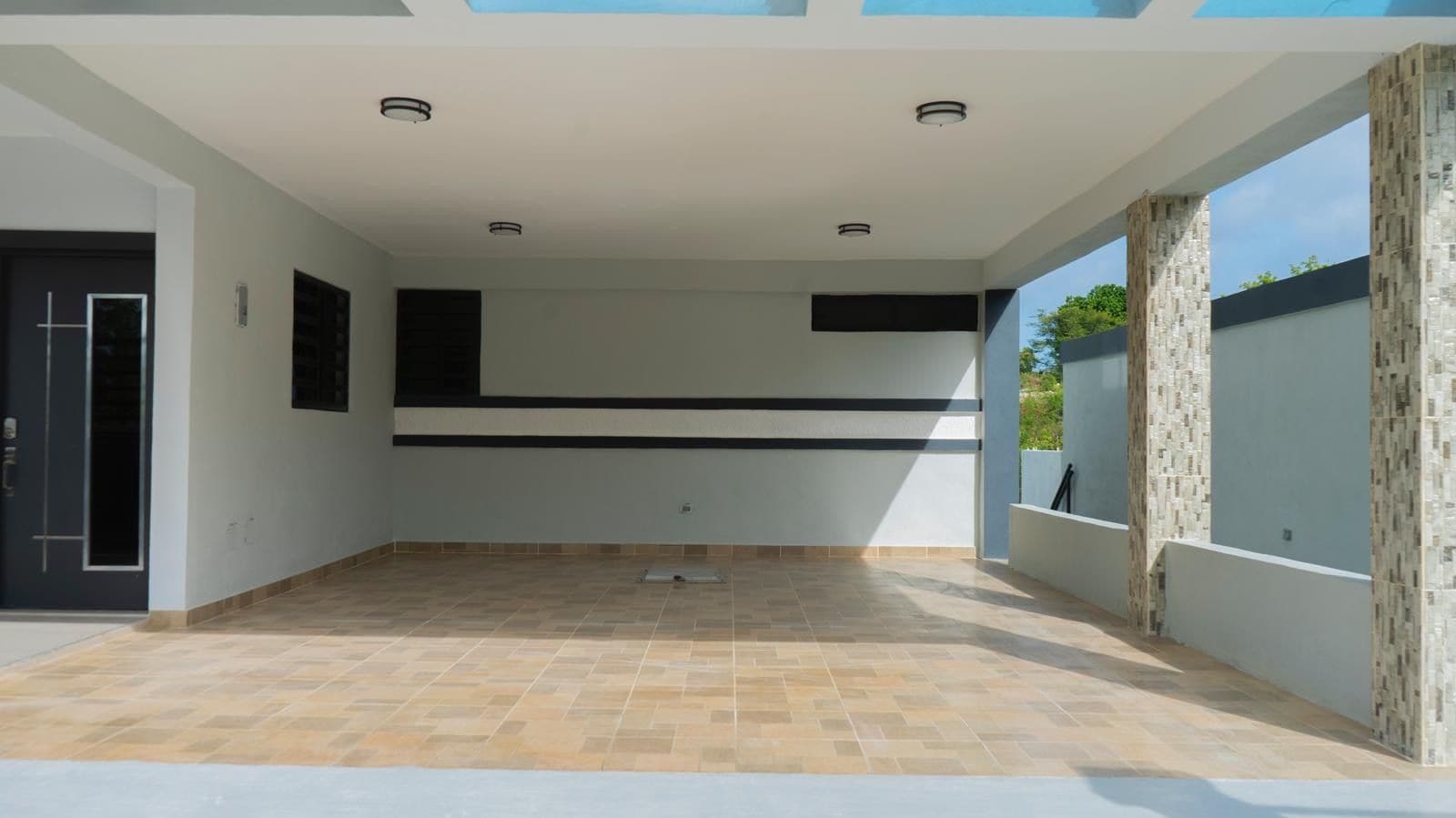 A spacious indoor area with a tiled floor, a black horizontal stripe on the wall, and a door on the left.