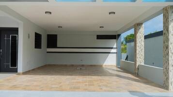 A spacious indoor area with a tiled floor, a black horizontal stripe on the wall, and a door on the left.