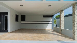 A spacious indoor area with a tiled floor, a black horizontal stripe on the wall, and a door on the left.