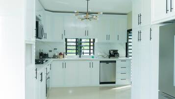 A modern kitchen with white cabinetry, a built-in dishwasher, and a coffee maker.