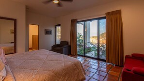 Ein Hotelzimmer mit einem großen Bett, einer Sitzecke mit einem Sessel und einem Balkon mit Blick auf die Stadt.