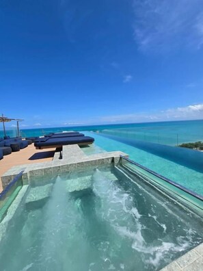 Ein klarer, blauer Himmel, ein Pool mit Wasserrutsche und Liegestühle.