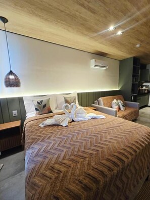 Ein Hotelzimmer mit einem großen Bett, einem Nachttisch, einem Sessel und einer Hängeleuchte.