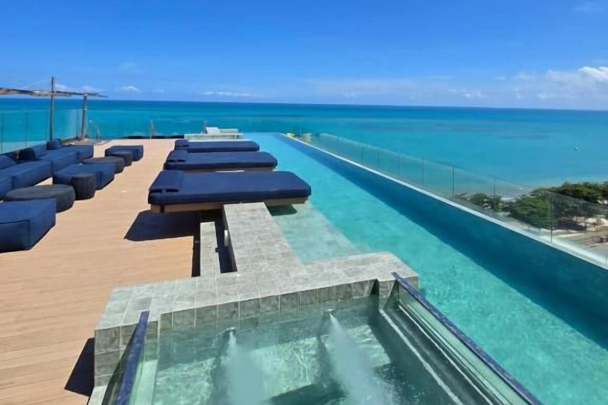 Ein Poolbereich mit Liegestühlen und freiem Blick auf den Ozean.