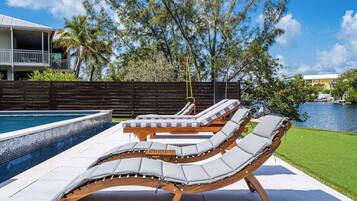 Un área junto a la piscina con sillones de descanso y un jacuzzi.