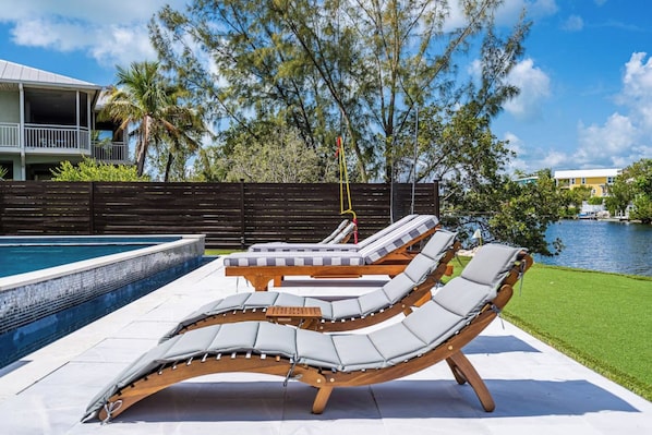 A poolside area with lounge chairs and a hot tub.