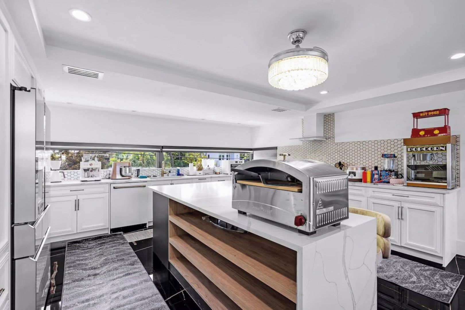 A modern kitchen with a built-in pizza oven, a popcorn machine, and a view of the outdoors.