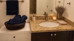 A bathroom with a large mirror, a sink, a towel rack, and a basket of towels. - Private Studio, Free parking, Laundry, 16 min to Downtown by city train (Toronto)