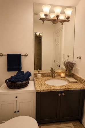 A bathroom with a large mirror, a sink, a towel rack, and a basket of towels.