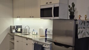 A modern kitchen with white cabinets, stainless steel appliances, and a patterned rug. - Private Studio, Free parking, Laundry, 16 min to Downtown by city train (Toronto)