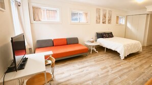 A compact room with a bed, a sofa, a small table, and a desk with a computer. - Private Studio, Free parking, Laundry, 16 min to Downtown by city train (Toronto)