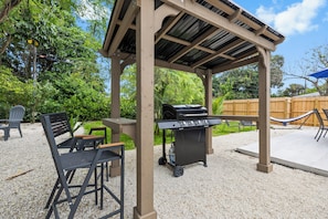 Ein Patio mit Pergola, Grill und Sitzgelegenheiten.