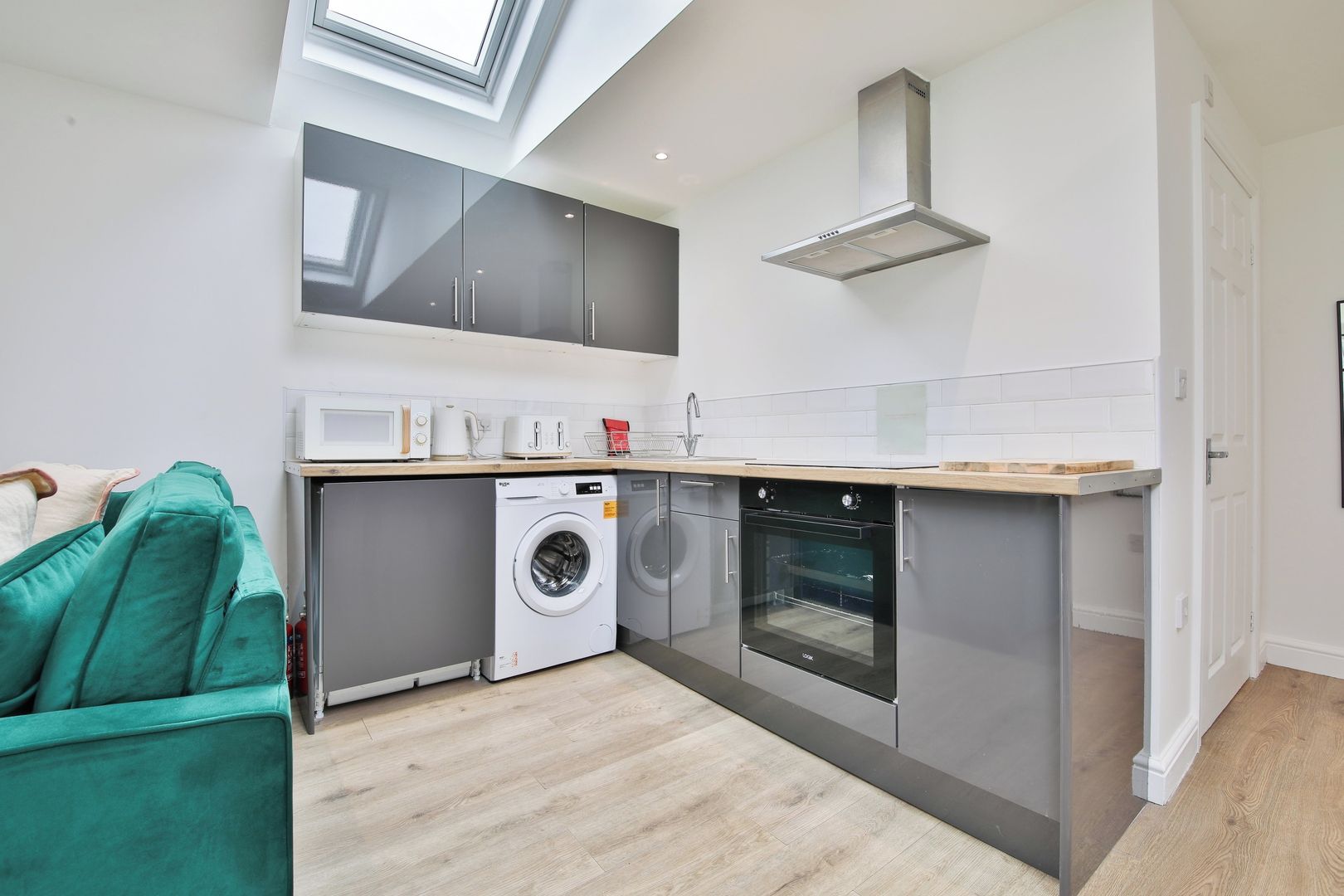 A compact kitchen with a washing machine, oven, and microwave.