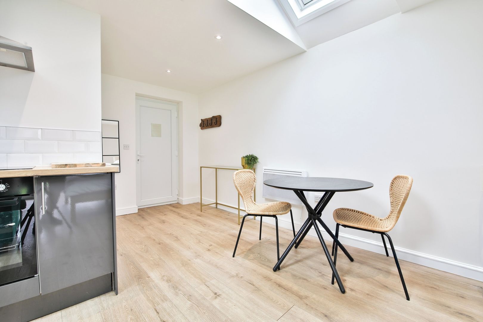 A modern kitchen with a built-in oven and a dining area with a round table and wicker chairs.