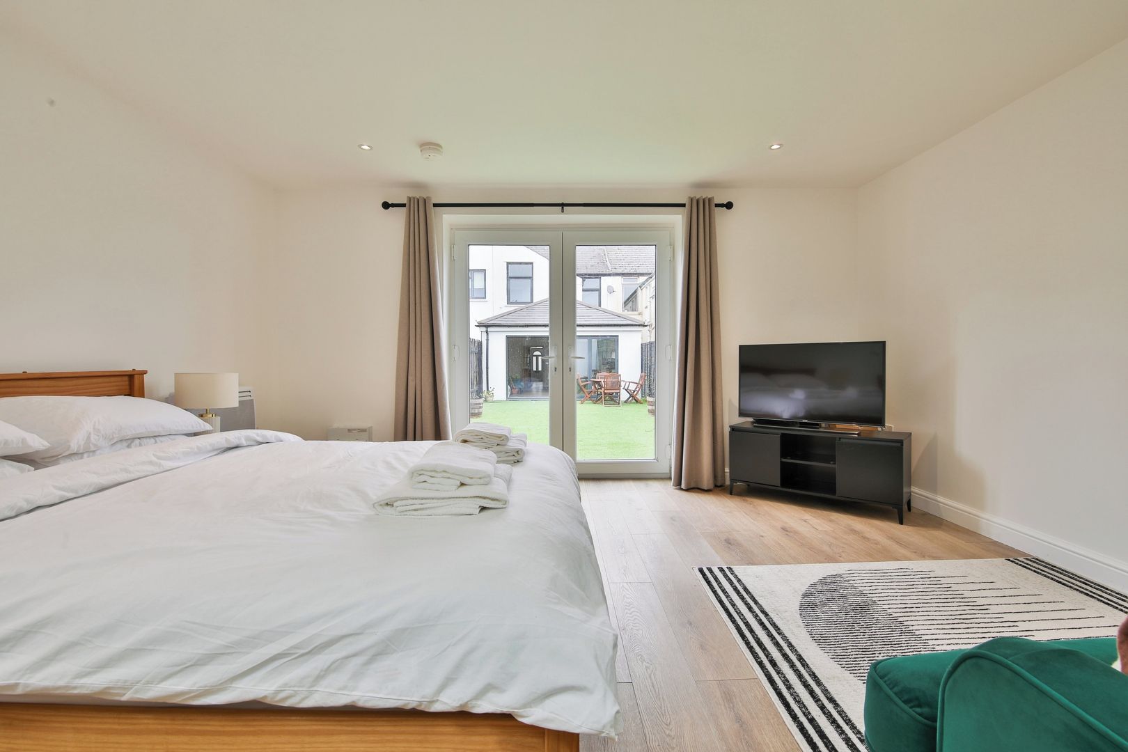 A hotel room with a bed, a TV, and a view of the outside.