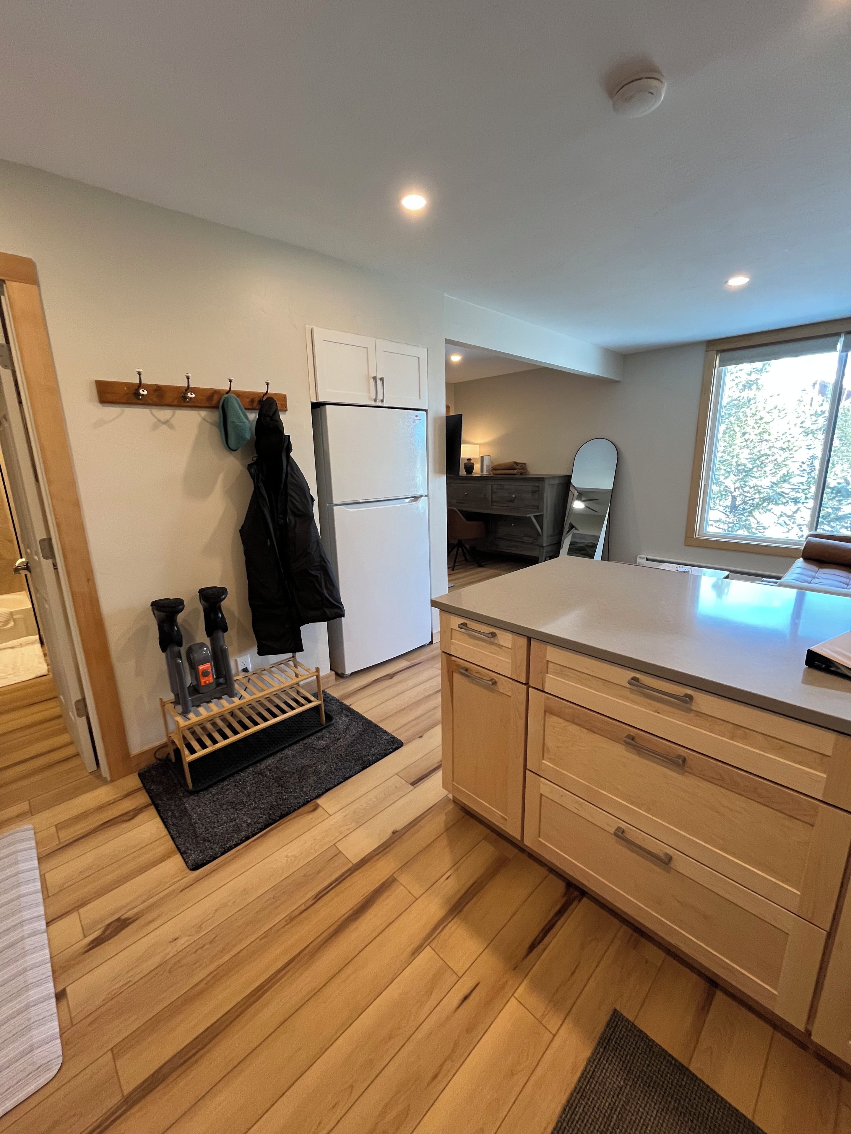 A modern kitchen with wooden cabinets, a built-in oven, and a window providing natural light.