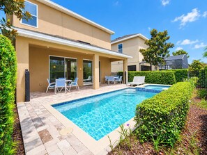 Ein Wohnhaus mit Swimmingpool, Terrassenmöbeln und einer überdachten Sitzgelegenheit im Freien.