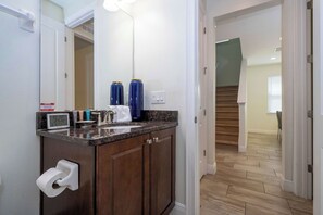A modern bathroom with a sink, toilet paper holder, and a mirror. - 14 Min to Disney, Modern Home for 10 Guests (Kissimmee)