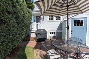 Une terrasse avec un barbecue, des sièges d’extérieur et un parasol.