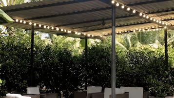 An outdoor seating area with wicker furniture and a covered roof.