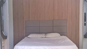 A bed with a headboard against a wooden panel wall.