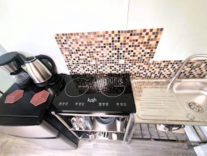 A kitchen with a black stove, a coffee maker, and a sink.
